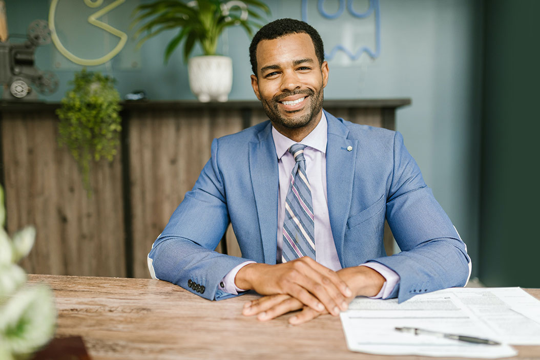 mortgage broker in a powder blue suit, smiling across a desk